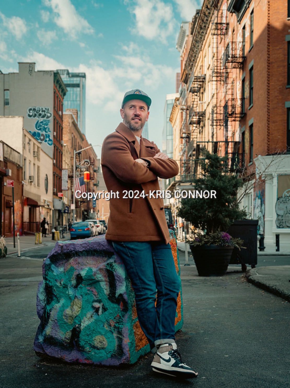 Ben Gollan Leaning against a rock with graffiti on it